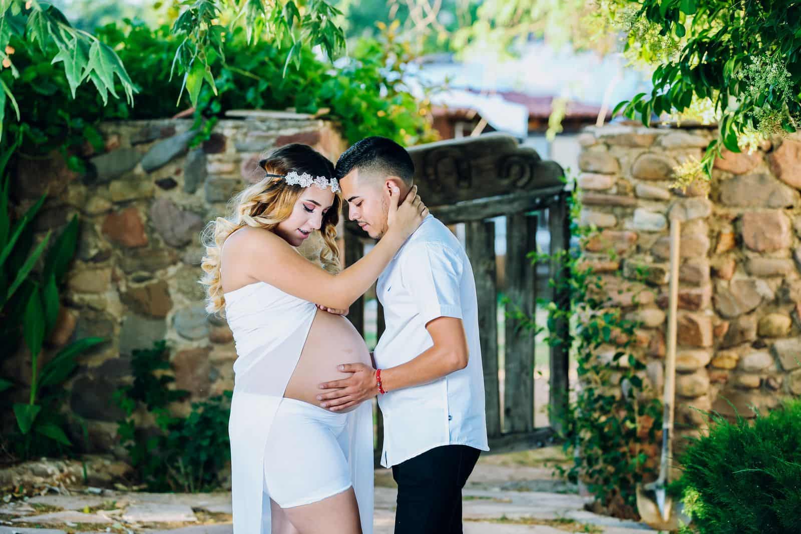 A pregnant couple embracing outdoors
